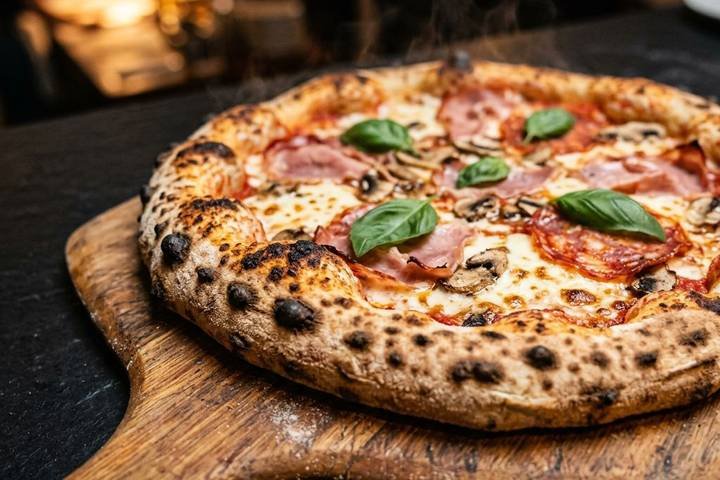 Pizza sortie du four sur une pelle en bois